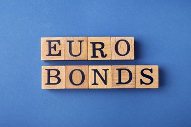 Word Eurobonds made of wooden cubes with letters on blue background, flat lay