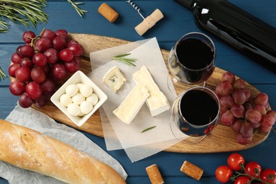 Flat lay composition with red wine and snacks on blue wooden table