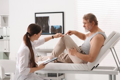 Orthopedist examining patient with injured knee in clinic