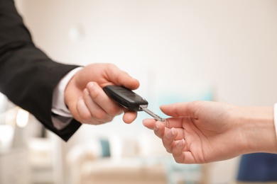 Man giving car key to woman indoors, closeup