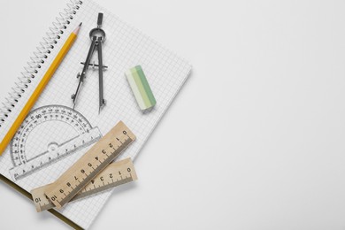 Photo of Different rulers, compass, pencil and notebook on white background, top view. Space for text