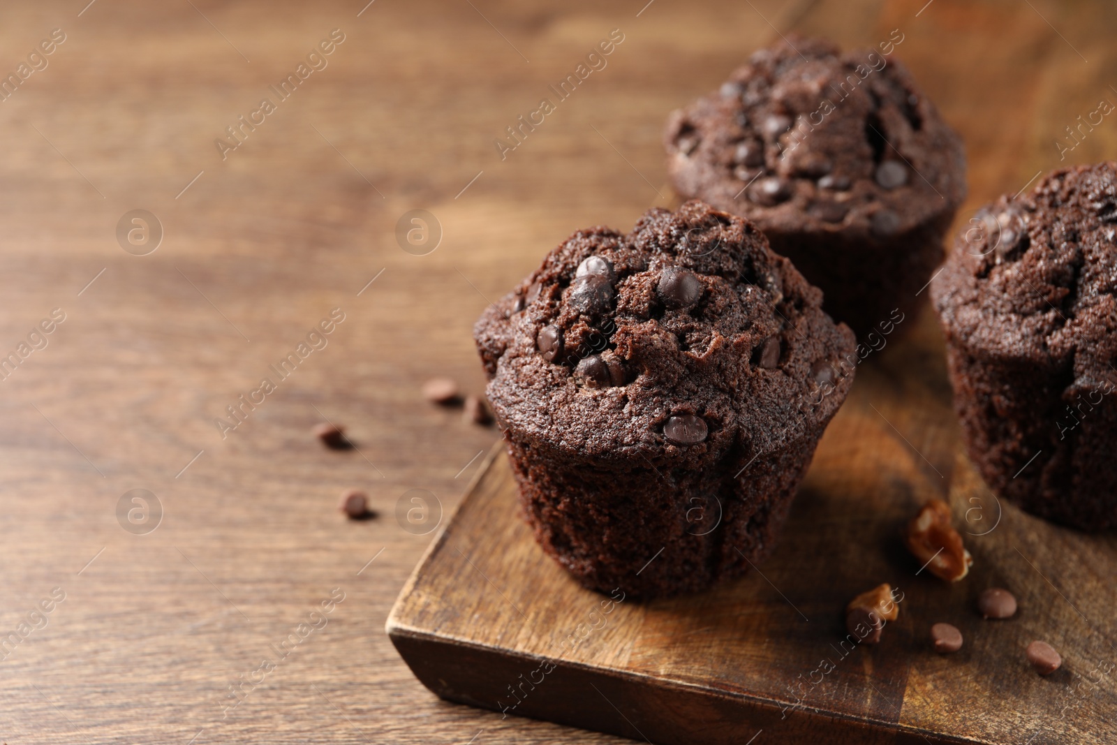 Photo of Delicious chocolate muffins on wooden table, closeup. Space for text