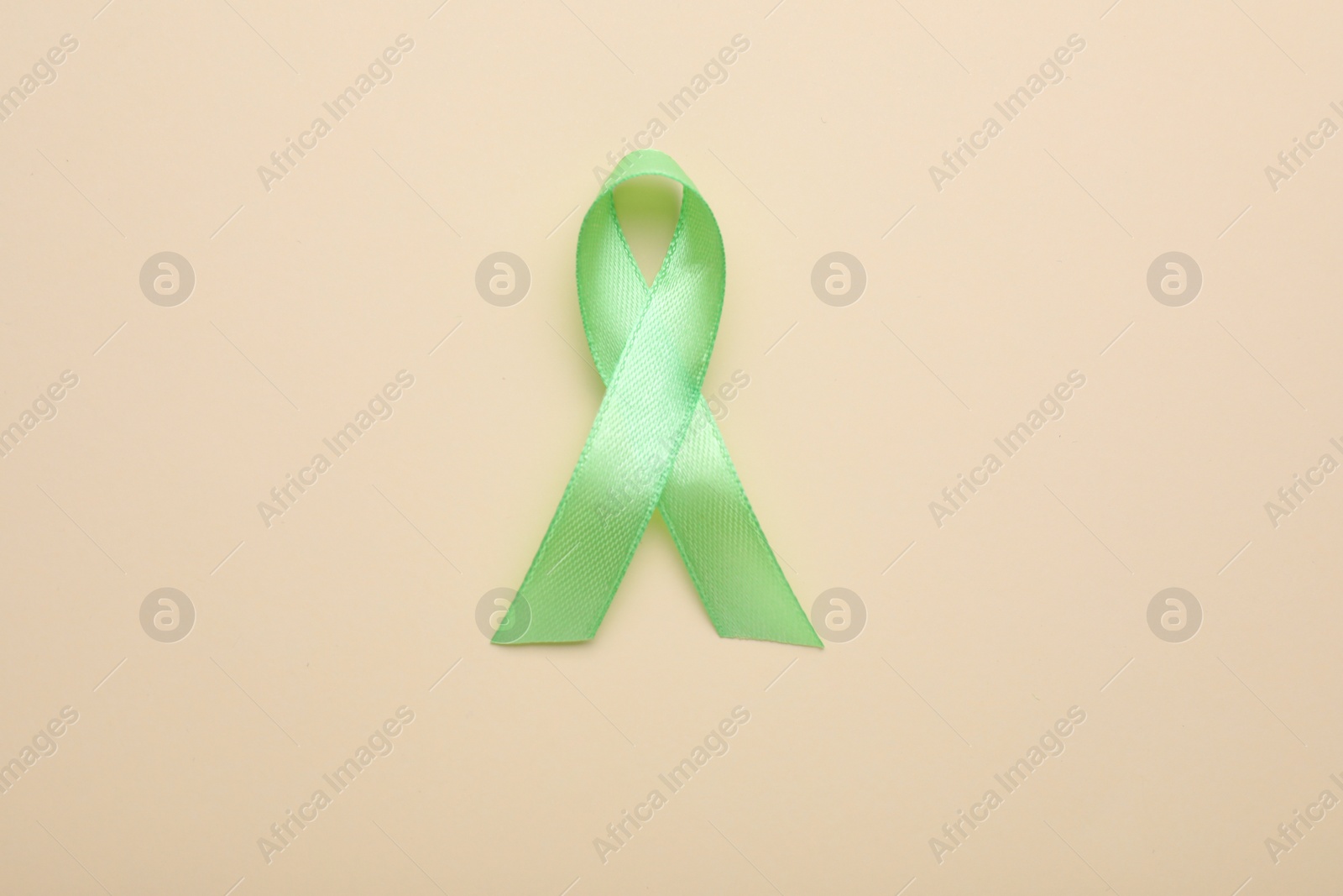 Photo of World Mental Health Day. Green ribbon on color background, top view