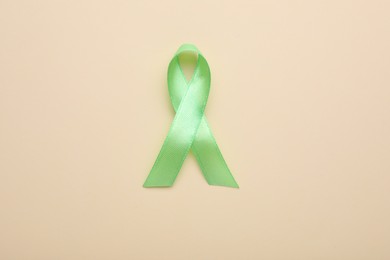 Photo of World Mental Health Day. Green ribbon on color background, top view