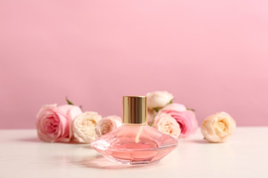 Bottle of perfume with beautiful roses on table