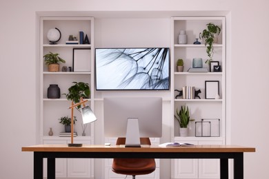 Photo of Cosy workplace with computer near tv area. Interior design