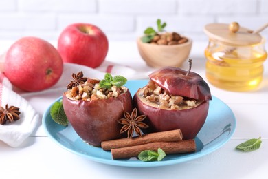 Photo of Tasty baked apples with nuts, honey, spices and mint on white wooden table