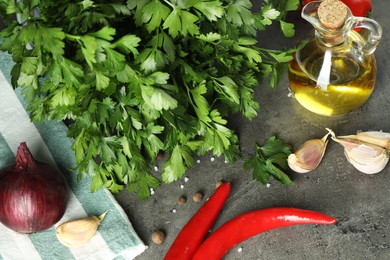 Photo of Fresh parsley, oil and other products on grey table, above view
