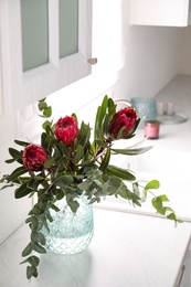 Bouquet with beautiful protea flowers on countertop in kitchen. Interior design