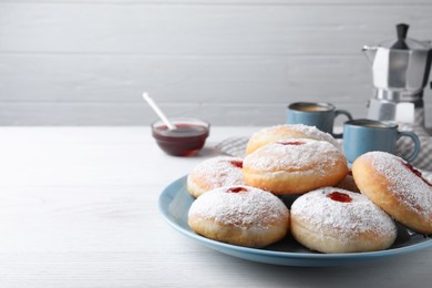 Photo of Delicious donuts with jam and powdered sugar on white wooden table. Space for text