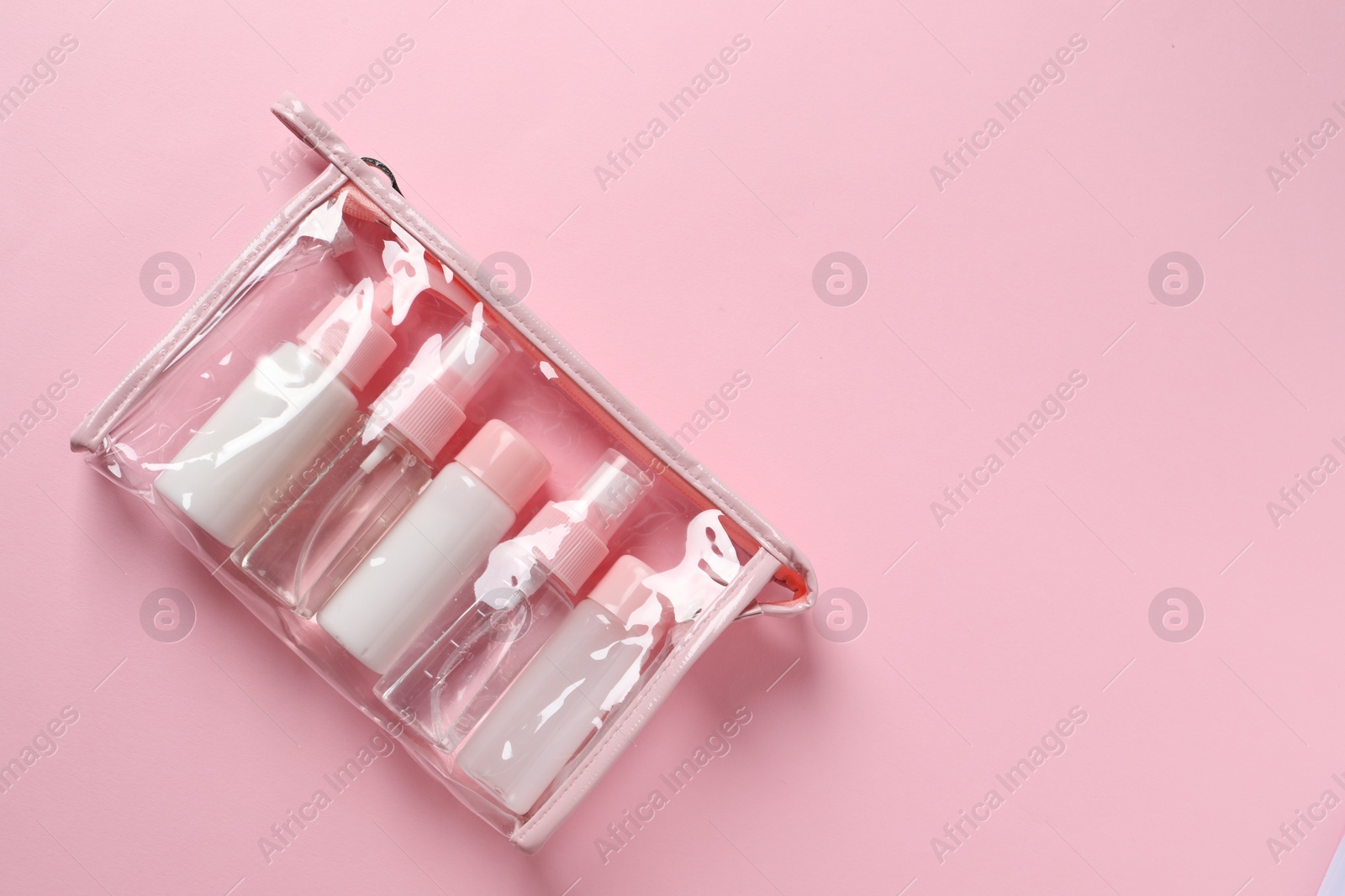 Photo of Cosmetic travel kit in plastic bag on pink background, top view. Space for text