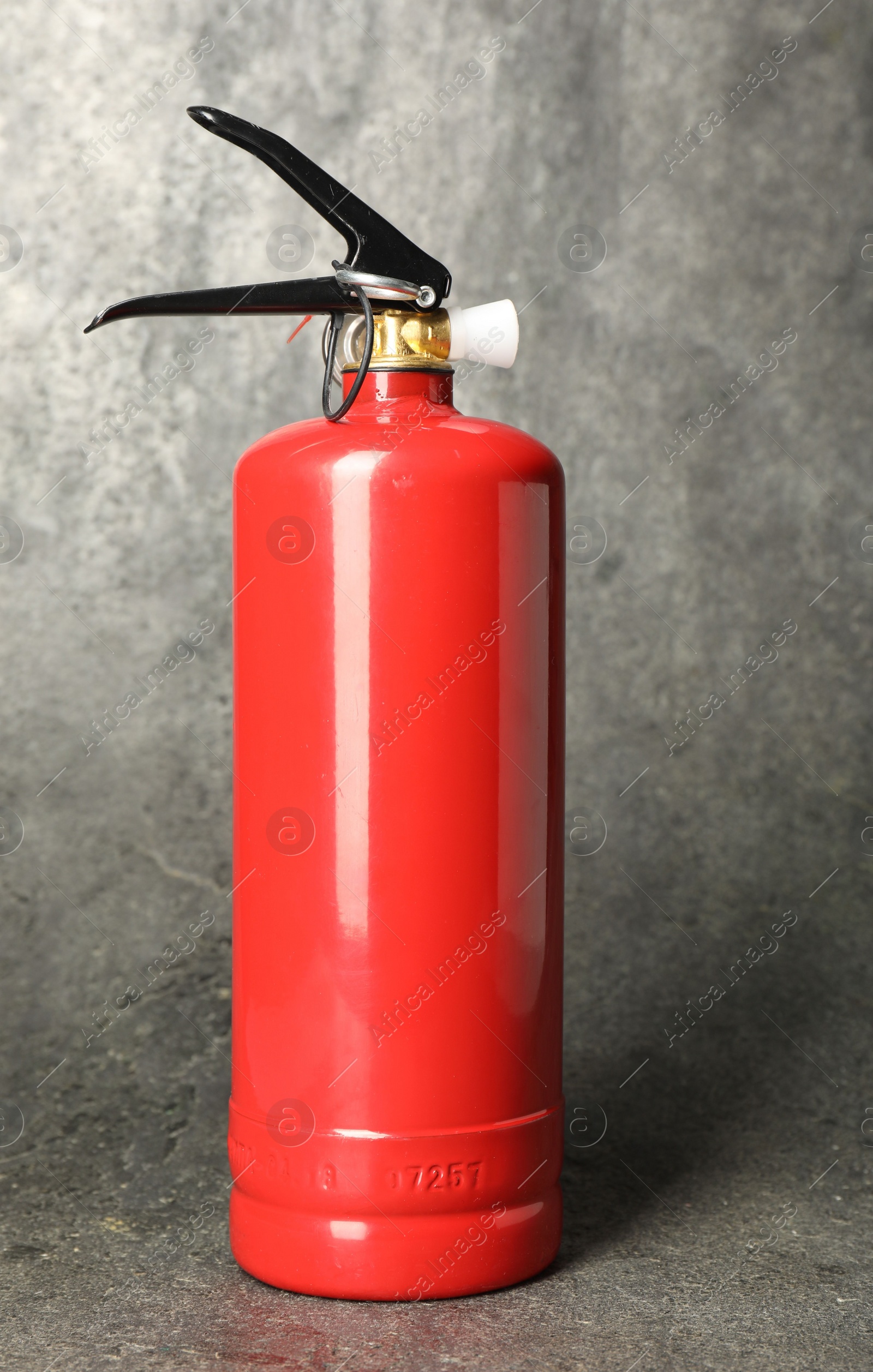 Photo of One red fire extinguisher on gray textured background