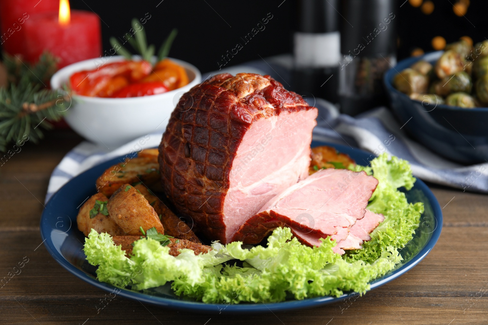 Photo of Delicious ham served with lettuce and potatoes on wooden table. Christmas dinner
