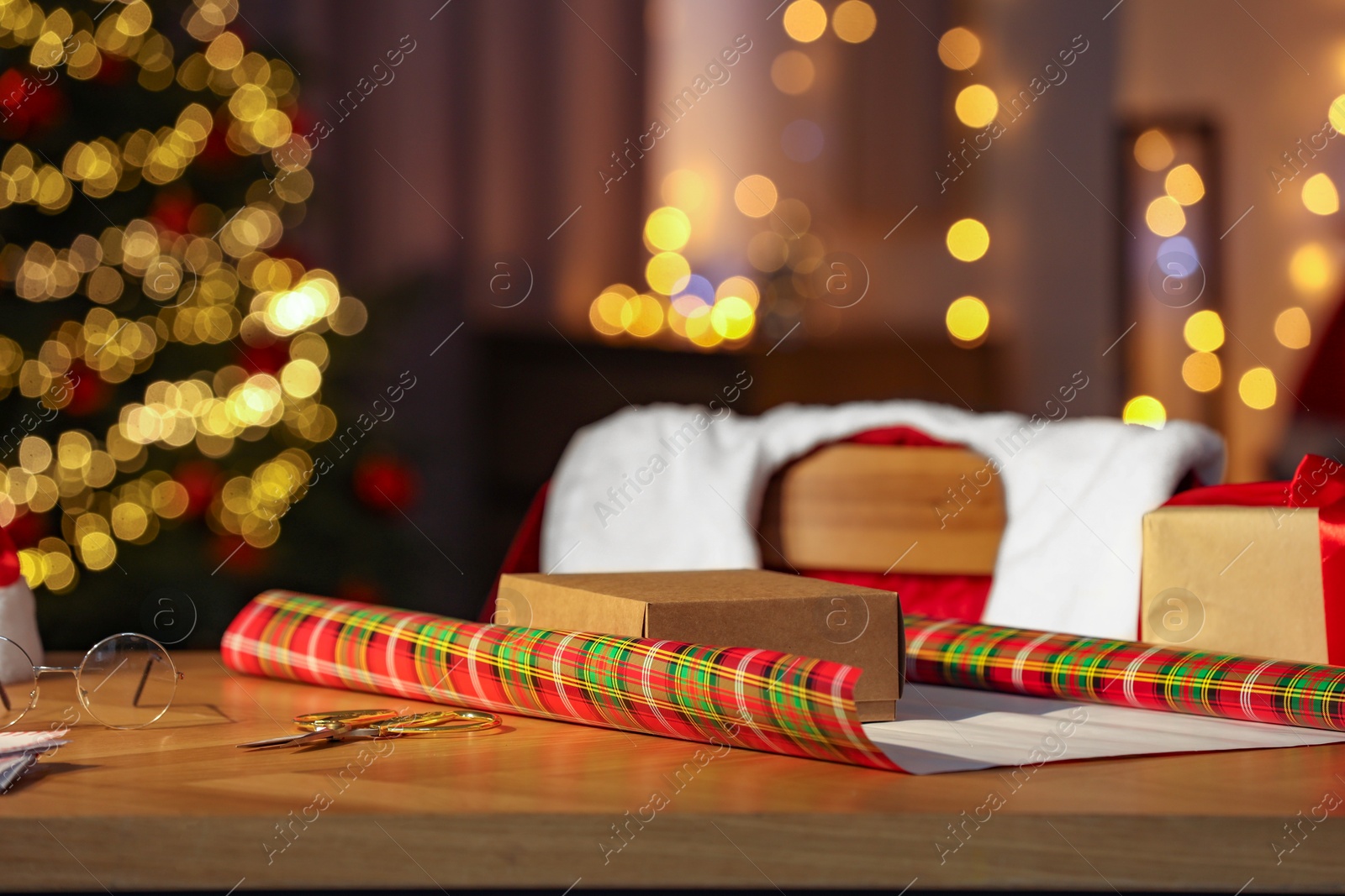 Photo of Santa's Claus workplace. Gift box and wrapping paper on table in room with Christmas tree