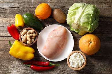 Photo of Healthy meal. Different vegetables and raw chicken breast on wooden table, flat lay