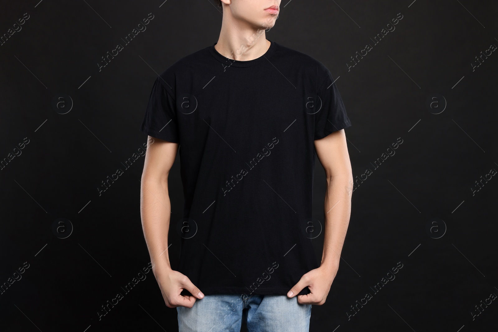 Photo of Man wearing stylish t-shirt on black background, closeup. Mockup for design