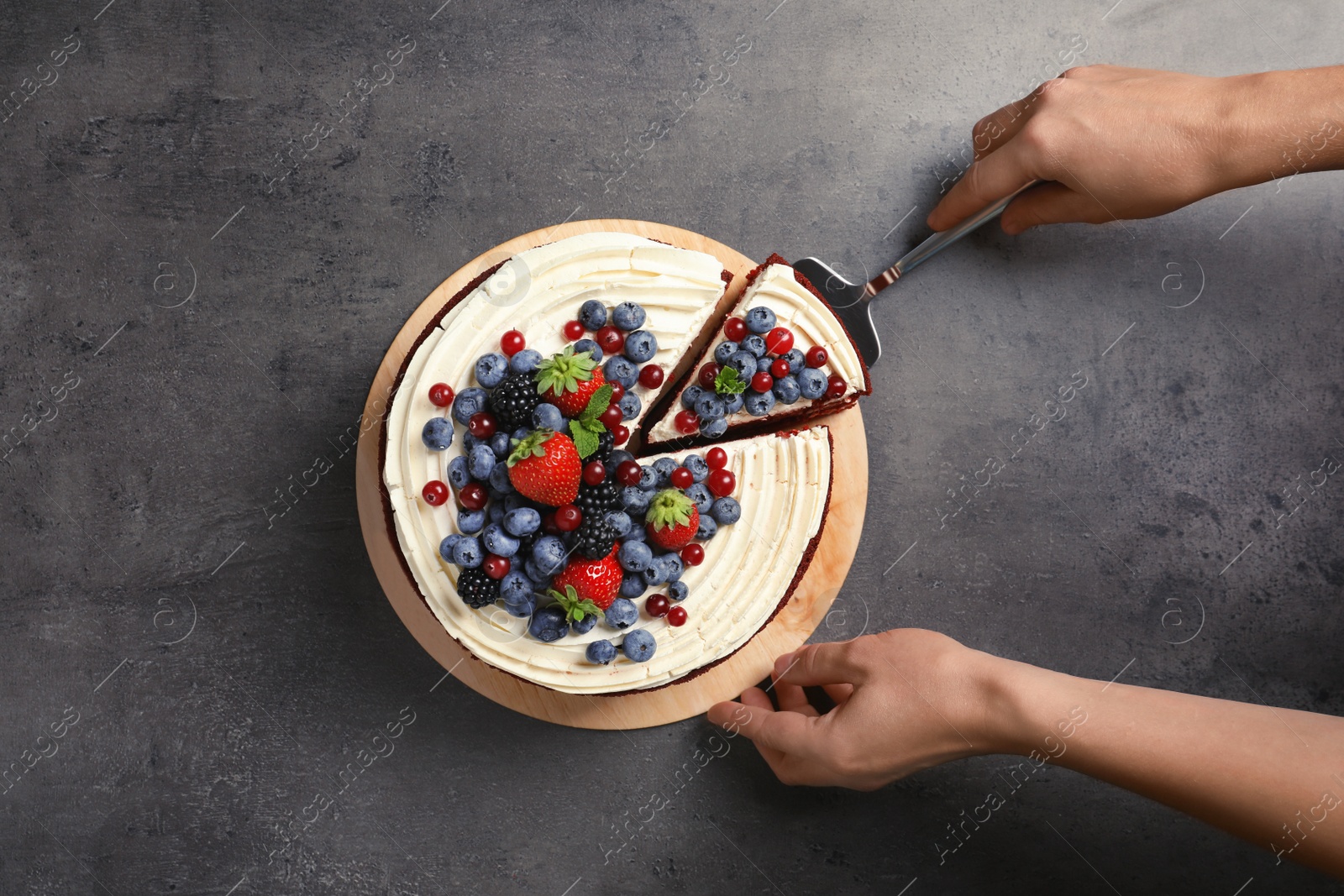 Photo of Woman taking piece of delicious homemade red velvet cake from table, top view