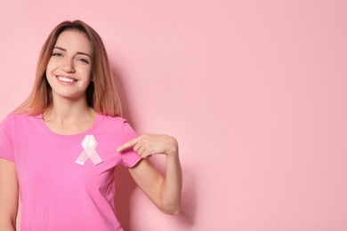 Photo of Woman with silk ribbon and space for text on color background. Breast cancer awareness concept