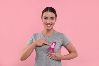 Photo of Beautiful young woman with pink ribbon on color background. Breast cancer awareness