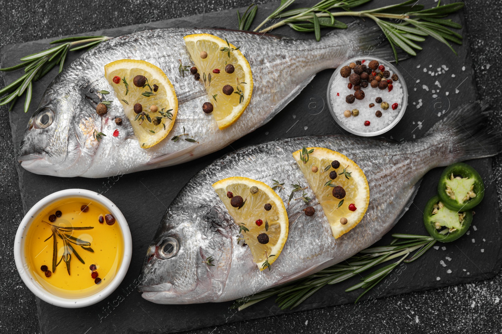 Photo of Fresh dorado fish and ingredients on black table, flat lay