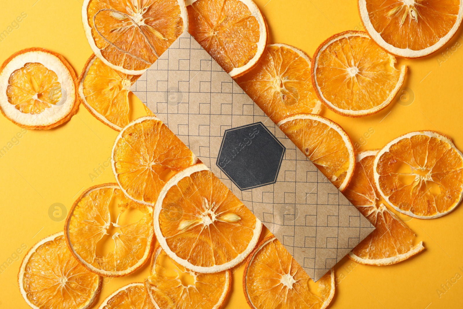 Photo of Scented sachet and dried orange slices on yellow background, flat lay