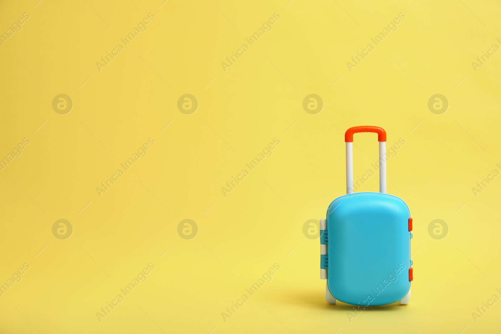 Photo of Stylish blue little suitcase on yellow background, space for text