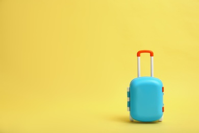 Photo of Stylish blue little suitcase on yellow background, space for text