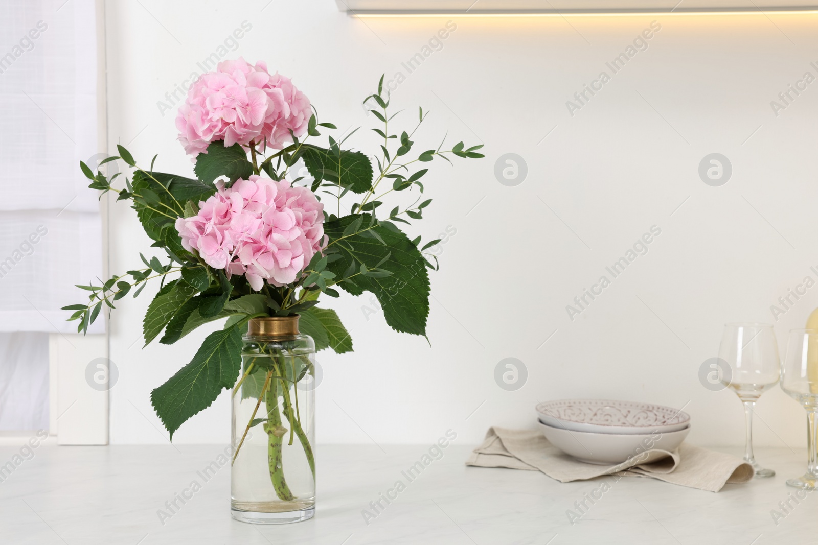 Photo of Beautiful pink hortensia flowers in vase on kitchen counter. Space for text