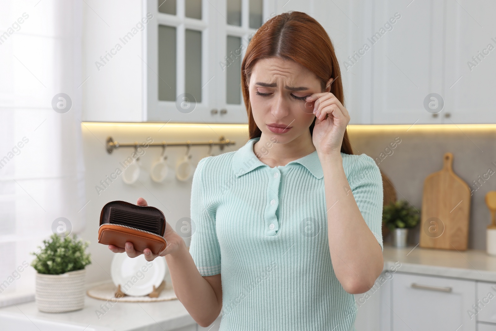 Photo of Upset woman with empty wallet at home