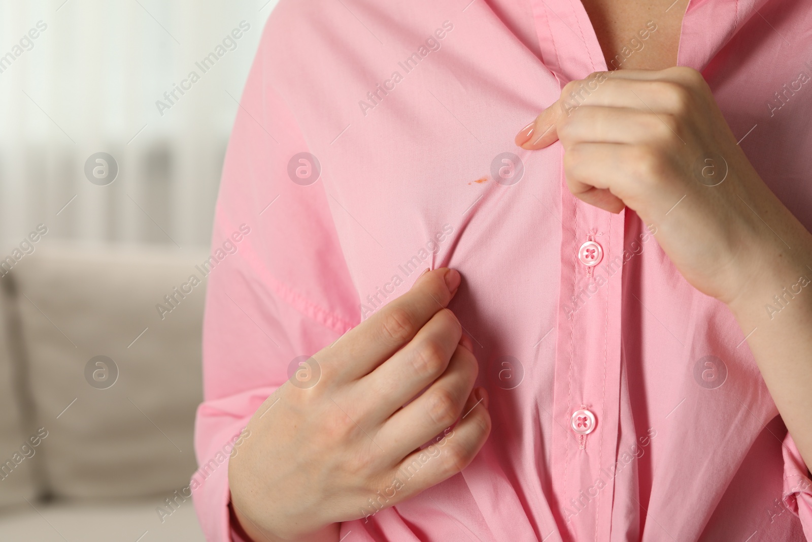 Photo of Woman showing stain on her shirt against blurred background, closeup