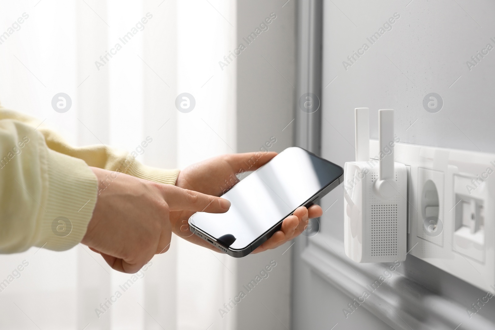 Photo of Woman using smartphone for wireless Wi-Fi repeater indoors, closeup