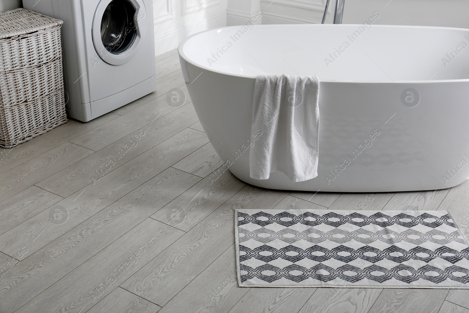 Photo of Stylish mat on floor near tub in bathroom. Interior design