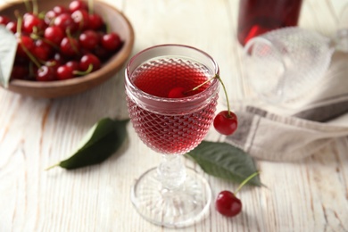 Delicious cherry wine with ripe juicy berries on white wooden table