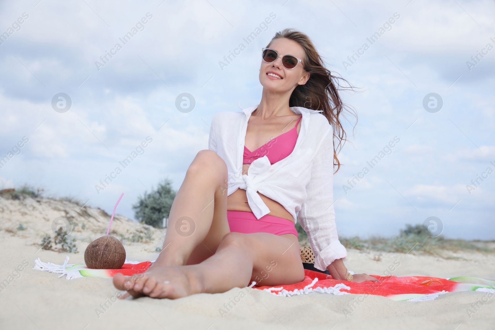 Photo of Beautiful woman with beach towel resting on sandy coast