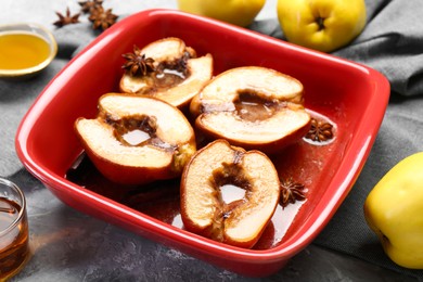 Photo of Tasty baked quinces with honey in dish on grey textured table, closeup