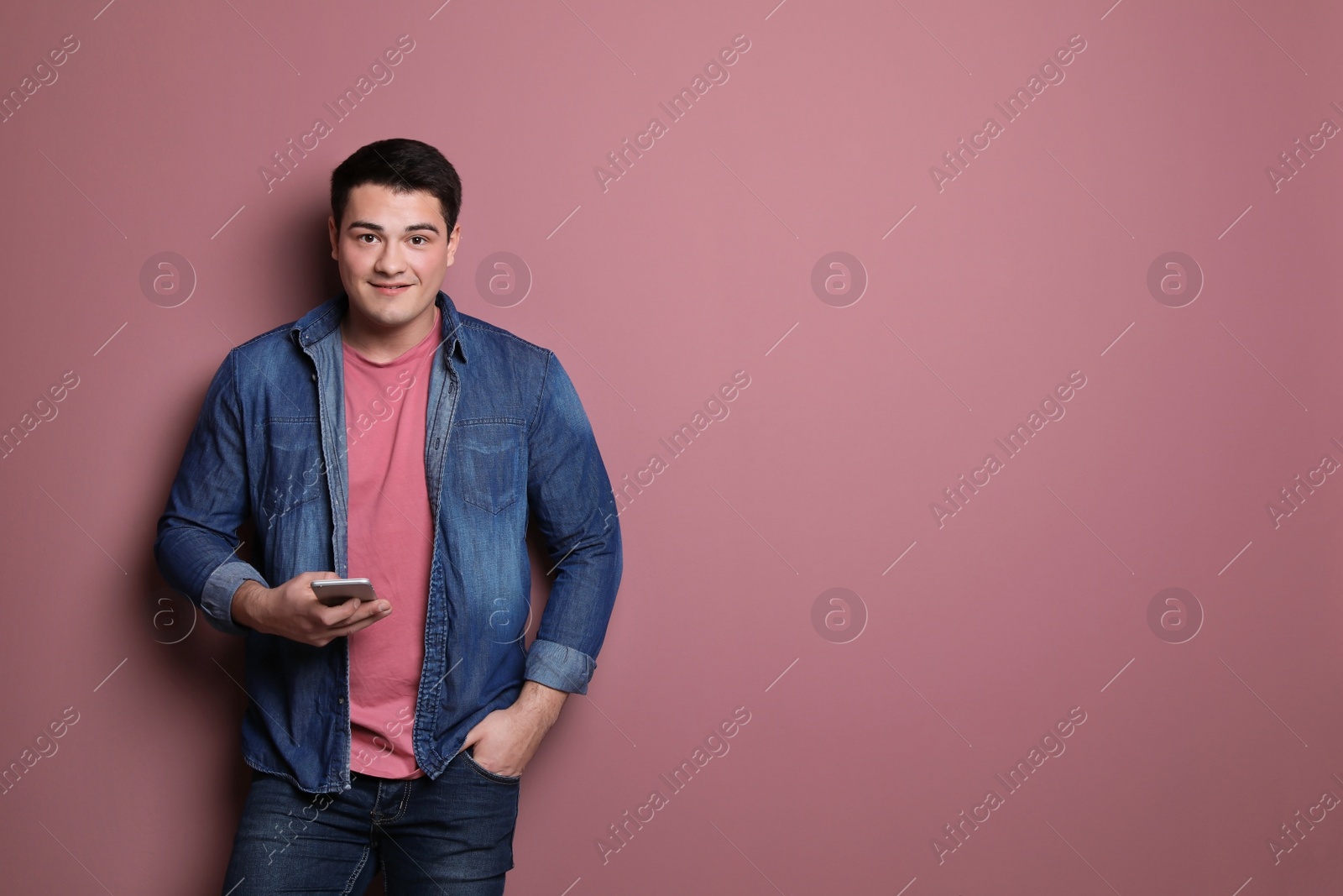 Photo of Portrait of confident young man with mobile phone on color background