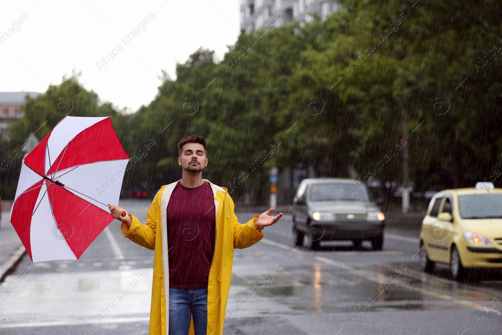 Photo of Handsome young man with bright umbrella outdoors on rainy day