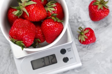 Photo of Kitchen scale with bowl of strawberries on grey textured table, flat lay