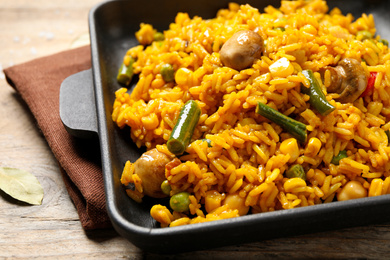 Photo of Delicious rice pilaf with vegetables on wooden table, closeup