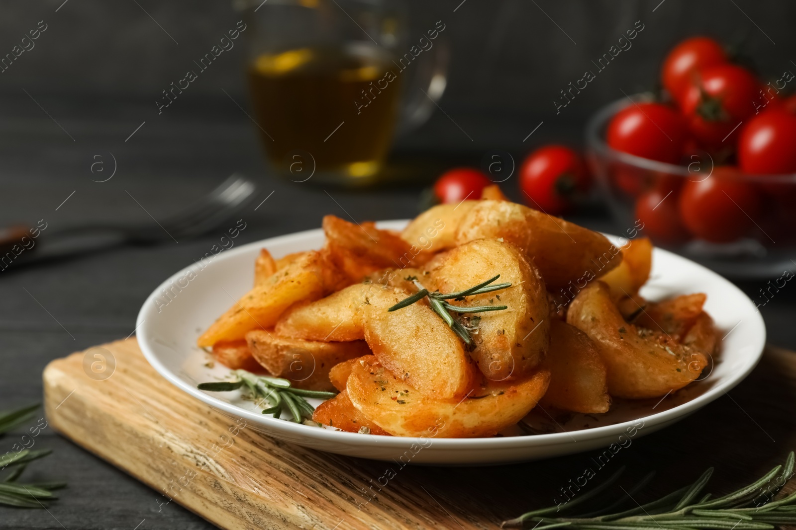 Photo of Plate with tasty baked potatoes and rosemary on wooden board