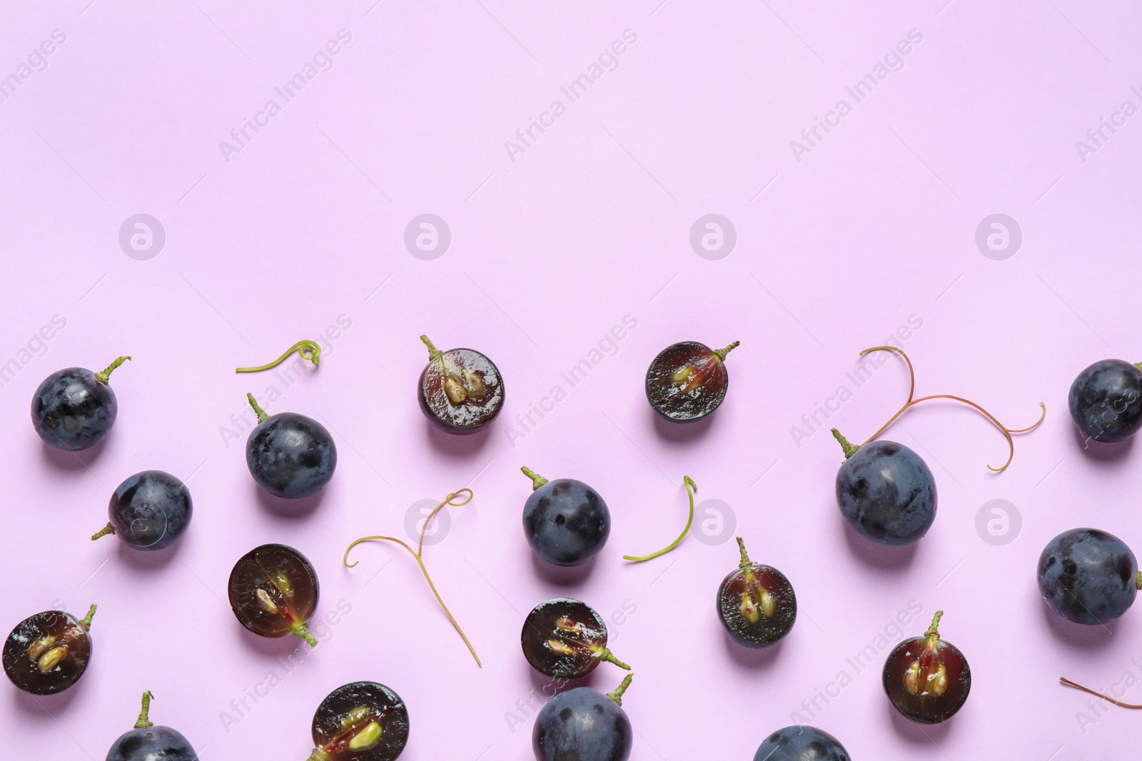 Photo of Flat lay composition with fresh ripe juicy grapes on lilac background, space for text