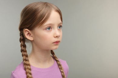 Little girl with hearing aid on grey background. Space for text