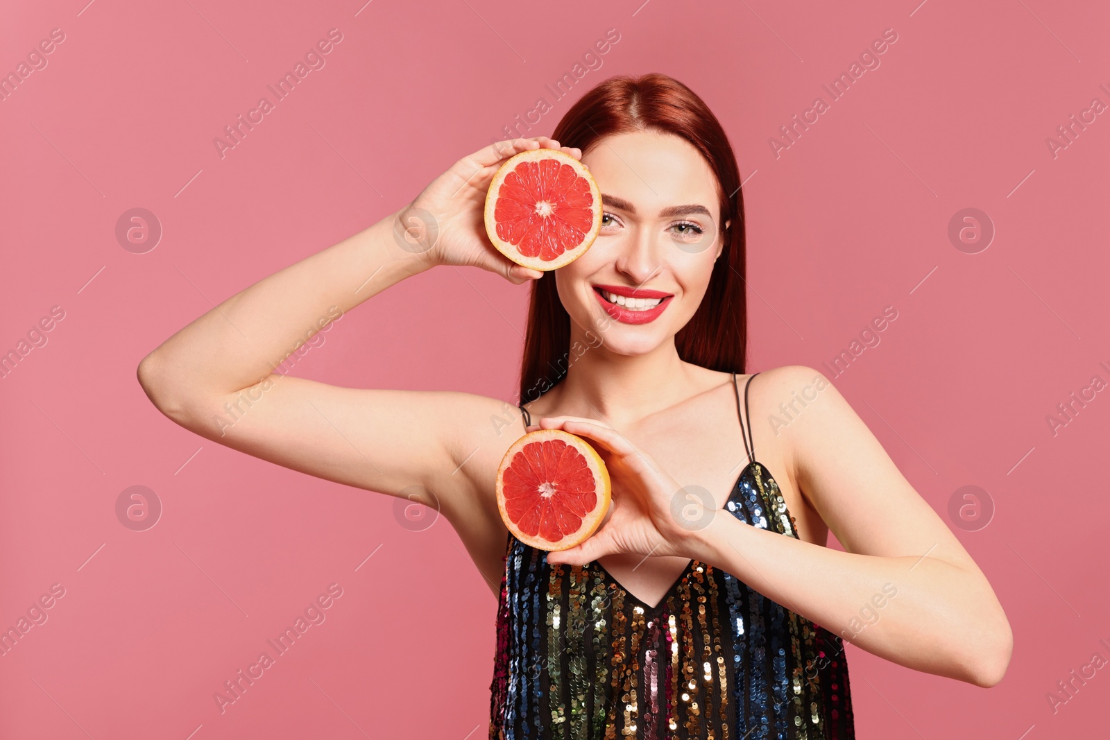 Photo of Happy woman with red dyed hair and grapefruits on pink background