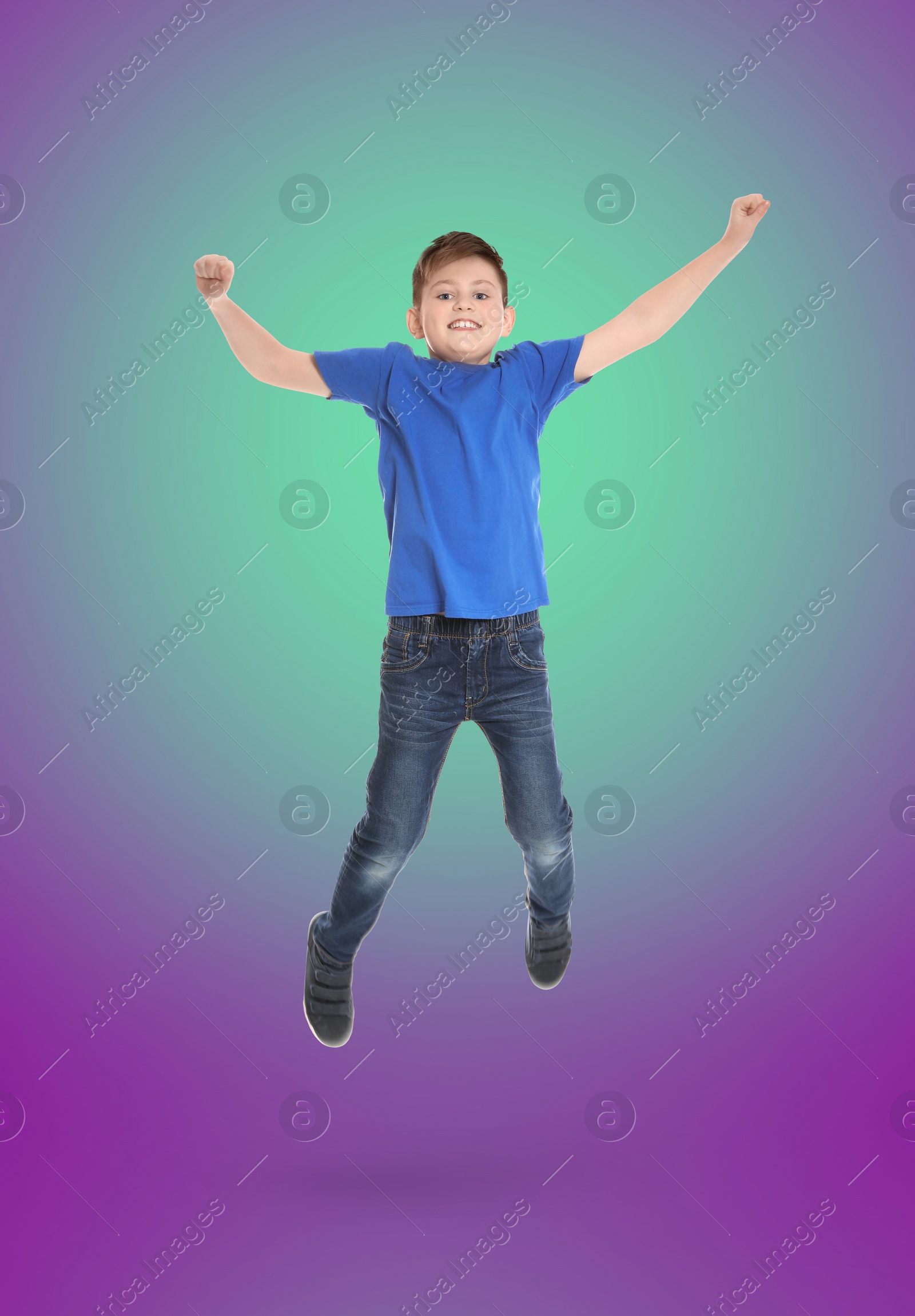 Image of Happy boy jumping on color gradient background