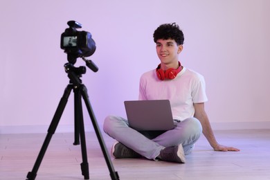 Photo of Smiling teenage blogger with laptop streaming indoors