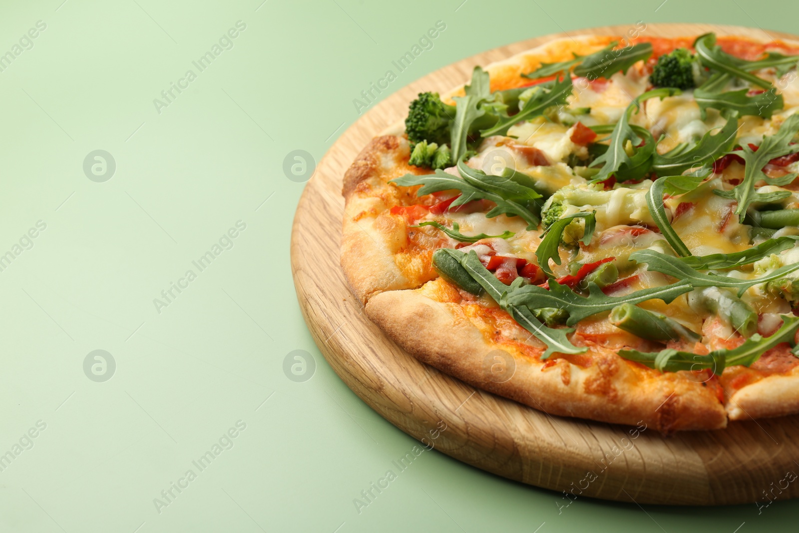 Photo of Delicious vegetarian pizza on green table, closeup. Space for text