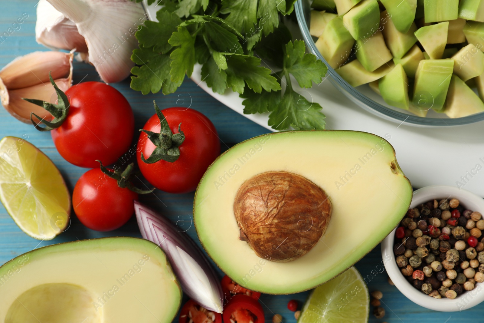 Photo of Fresh ingredients for guacamole on light blue wooden table, flat lay