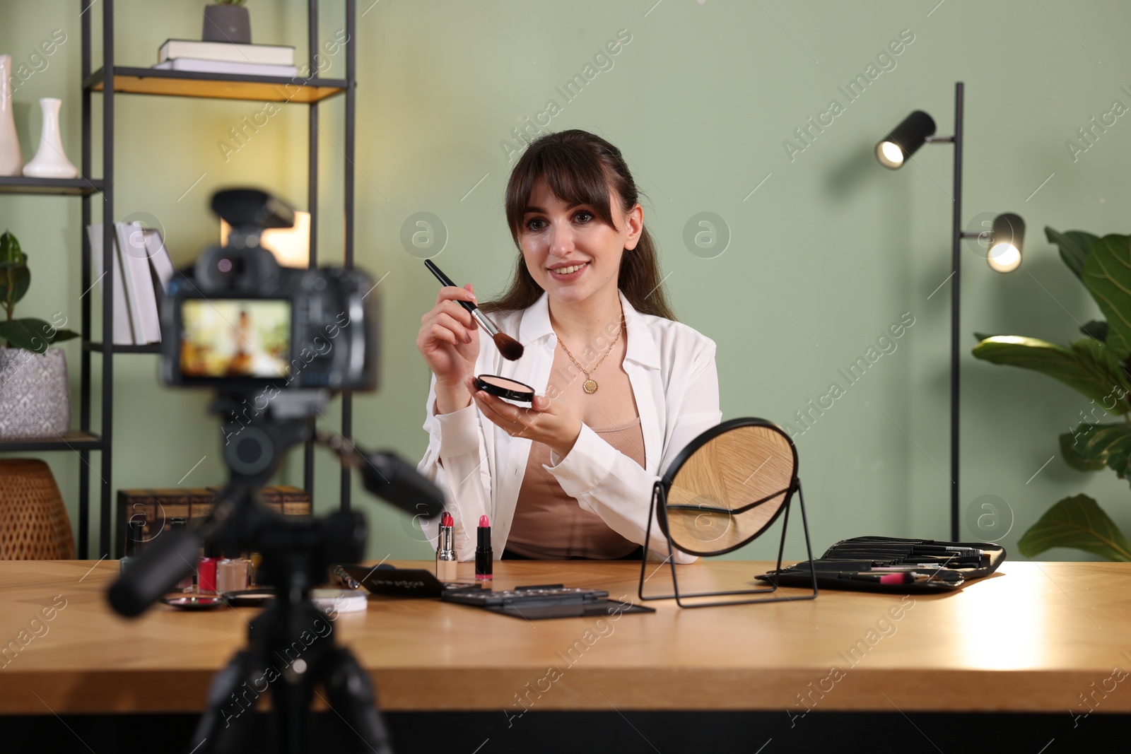 Photo of Smiling beauty blogger recording makeup tutorial at home