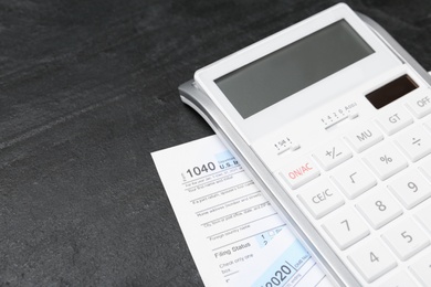 Photo of Calculator and documents on black stone table, closeup. Tax accounting
