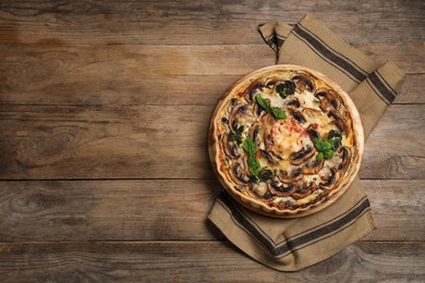 Delicious quiche with mushrooms and basil on wooden table, top view. Space for text